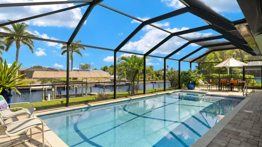 Villa Paradise Cove - a pool area with a large pool overlooking a wide canal - SWFL Vacation Rentals