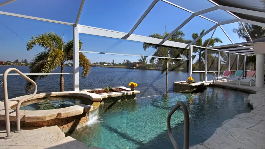 Villa Laguna - pool area with an infinity pool and attached spa overlooking an intersecting canal - SWFL Vacation Rentals